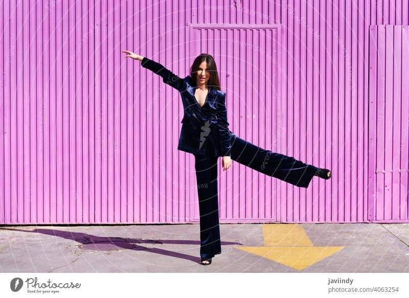 Woman wearing blue suit dancing near pink shutter. woman girl arms leg person fashion model lifestyle female urban background lady one elegant building blind