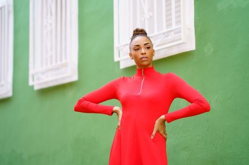 Young black woman in red dress in front of a green wall bow serious hairstyle model beauty fashion pretty portrait girl young female person lady summer white