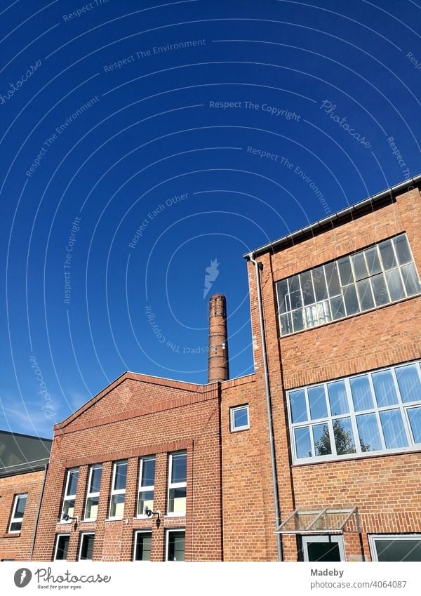 Old factory building and high factory chimney with beautiful facade in front of blue sky in sunshine in the hanseatic town Lemgo near Detmold in East Westphalia-Lippe