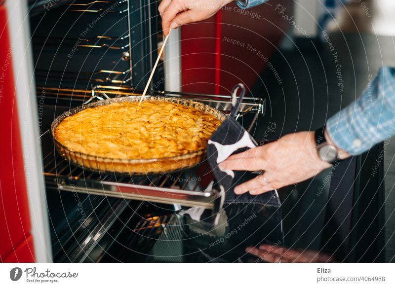 A woman checks with a wooden skewer if the apple pie is already baked Apple pie Baking Completed test kiln wooden sticks Cake Kitchen Woman cute Baked goods
