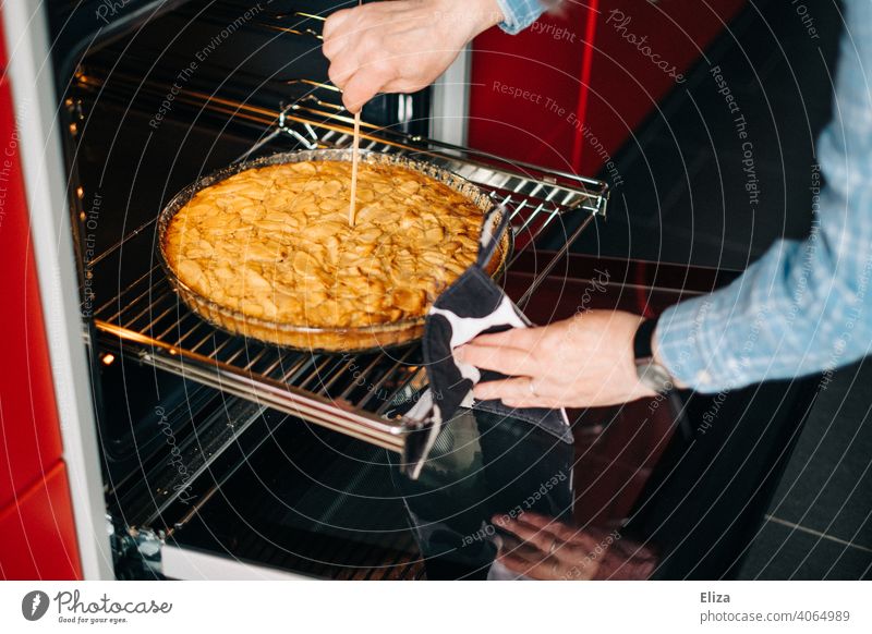 A woman checks with a wooden skewer if the apple pie is already baked Apple pie Baking Completed test kiln wooden sticks Cake Kitchen Woman cute Baked goods