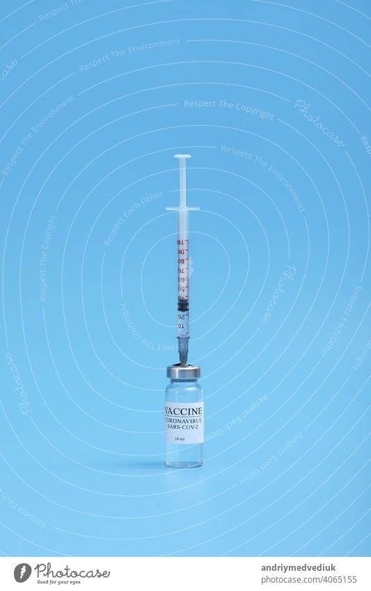 Medicine bottle with coronavirus vaccine covid-19. Medical glass vial and syringe for vaccination. liquid vaccine in laboratory, hospital or pharmacy concept isolated on blue background