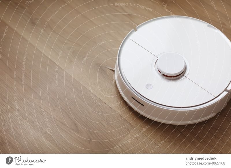Robot vacuum cleaner performs automatic cleaning of the apartment at a certain time. white robot vacuum cleaner. home cleaning. Smart home. selective focus