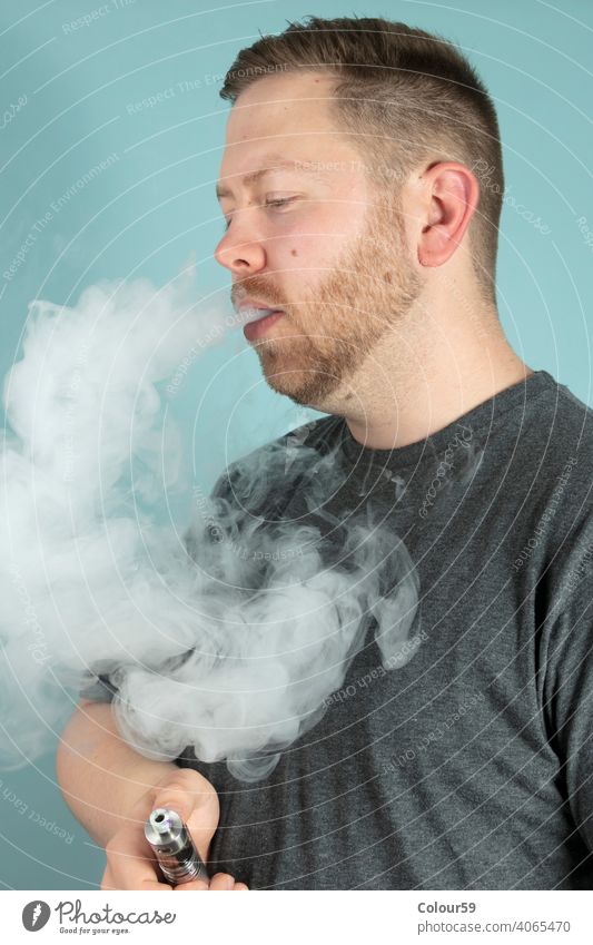 Young man vaping smoking an e-cigarette addictive cloud electronic exhaling nicotine smoke smoker stimulant unhealthy vape vaporizer vice holding aerosol