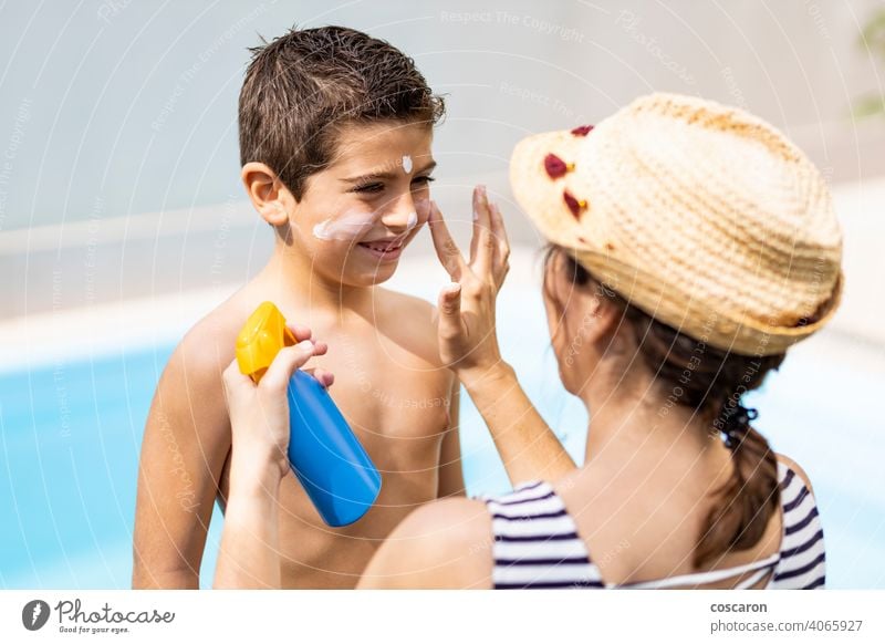 Mother aplying sunscreen to her son on a summer day apply applying beach boy care child childhood cosmetic cream face family happy health healthy holiday kid