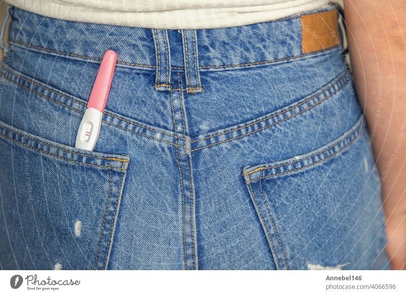 Young woman with positive pregnancy test in pocket of jeans close-up young waiting surprise pregnant motherhood maternity holding happiness girl fertility