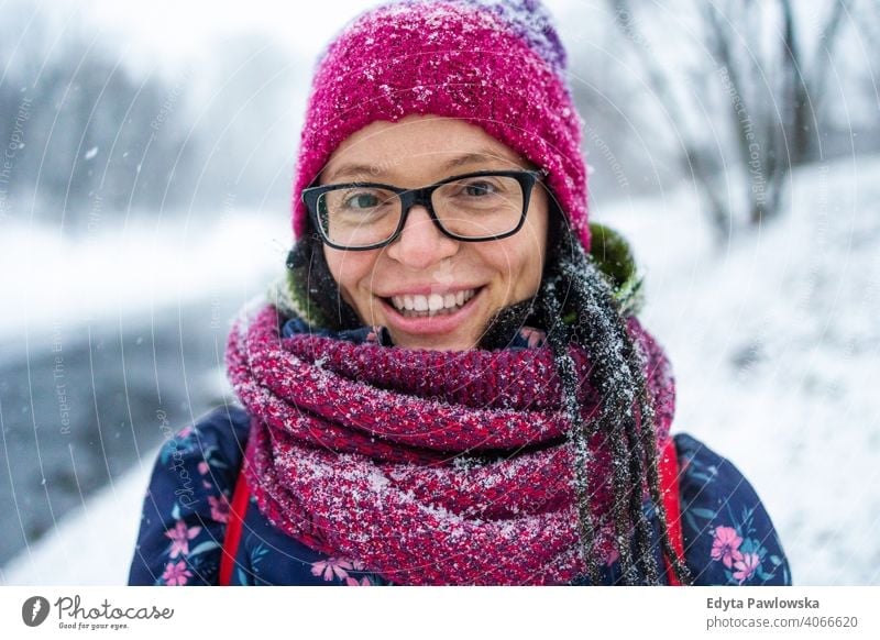 Portrait of woman in wooly hat and scarf in winter glasses outside natural healthy mitten trees gloves one snowflake christmas beauty attractive adult face