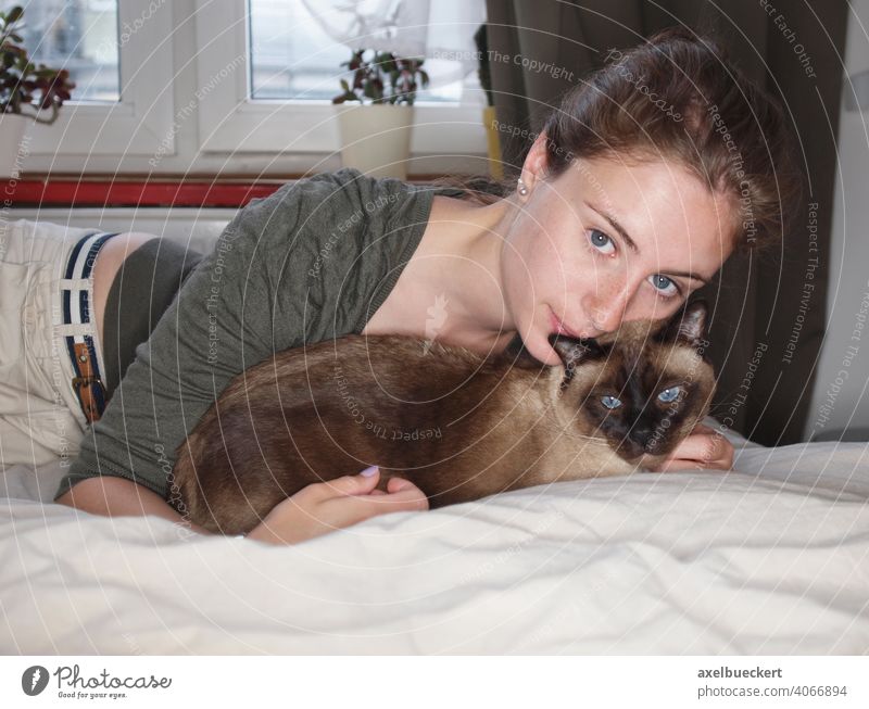 young woman cuddling with siamese cat on bed Bed Lie relaxing Lifestyle Bedroom Cozy Relaxation Young woman relaxation at home stay at home Leisure and hobbies