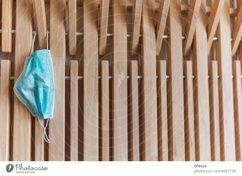medical blue mask hangs on a thick wooden hook on wooden hallway furniture. selective focus. wooden furniture from planks with gaps. end of quarantine indoor
