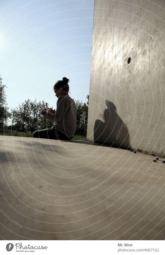 loneliness teenager Youth (Young adults) Girl Hair and hairstyles Chignon Sit Sun Shadow Concrete Concrete wall Concrete floor Sky Beautiful weather