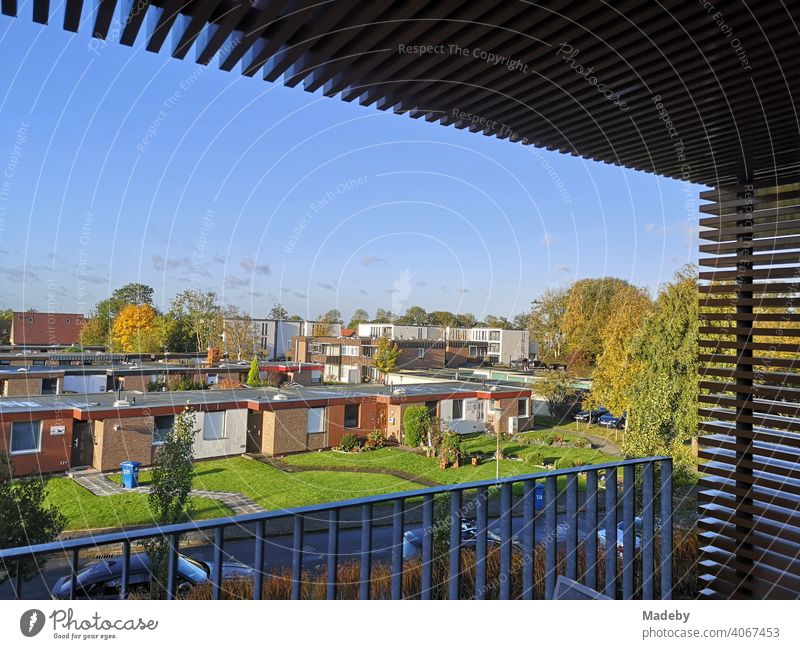 View from the balcony of a holiday flat in a modern apartment house onto a settlement with bungalows for tourists in the green at sunshine in Bensersiel near Esens at the coast of the North Sea in East Frisia in Lower Saxony