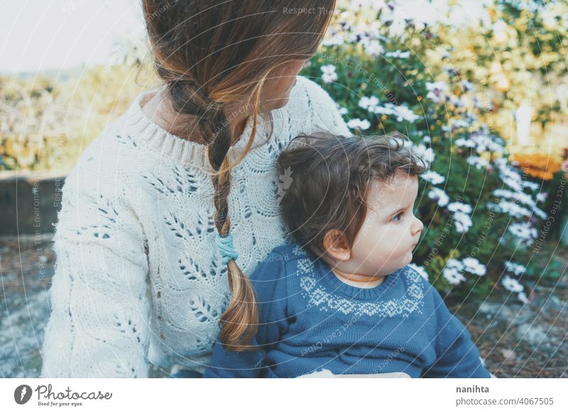 Young mom hugging her baby and enjoying a spring day in the garden family lifestyle love care child kid childhood springtime flowers nature natural hippie