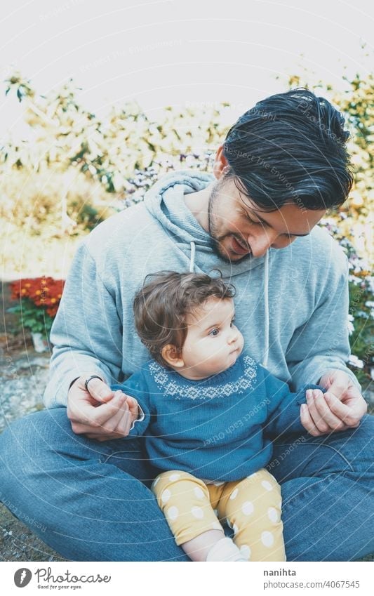 Young dad enjoying a sunny day with his baby in the garden father family love happiness care caring parenting lovely cute outdoors spring spring time nature