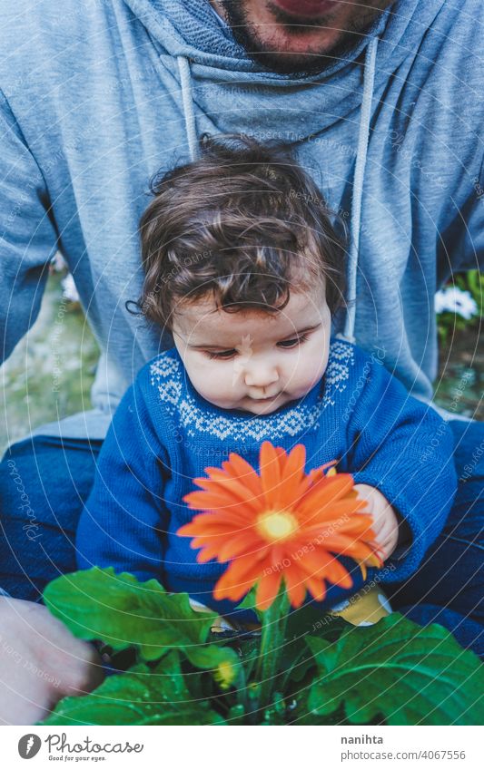 Little baby discovering a huge flower for first time spring happiness family family time dad father girl kid child toddler 9 month casual candid wear life