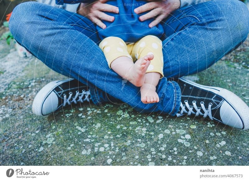 Close up of body parts of a baby of teenage fathers with her dad parent feet legs foot close close up casual sneakers barefeet teenage parenting family