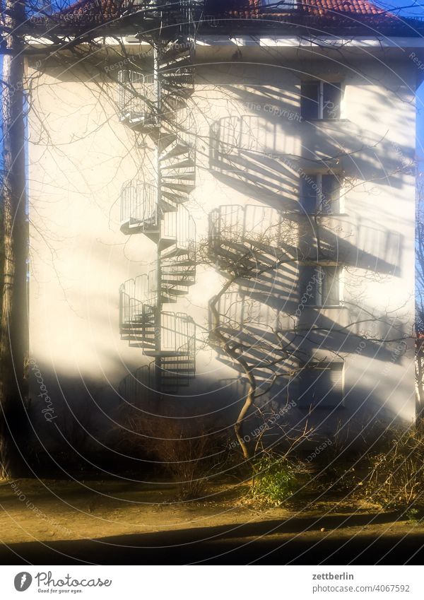 A spiral staircase and its shadow on the outside Fire wall Facade Window House (Residential Structure) Sky Sky blue Courtyard Interior courtyard downtown