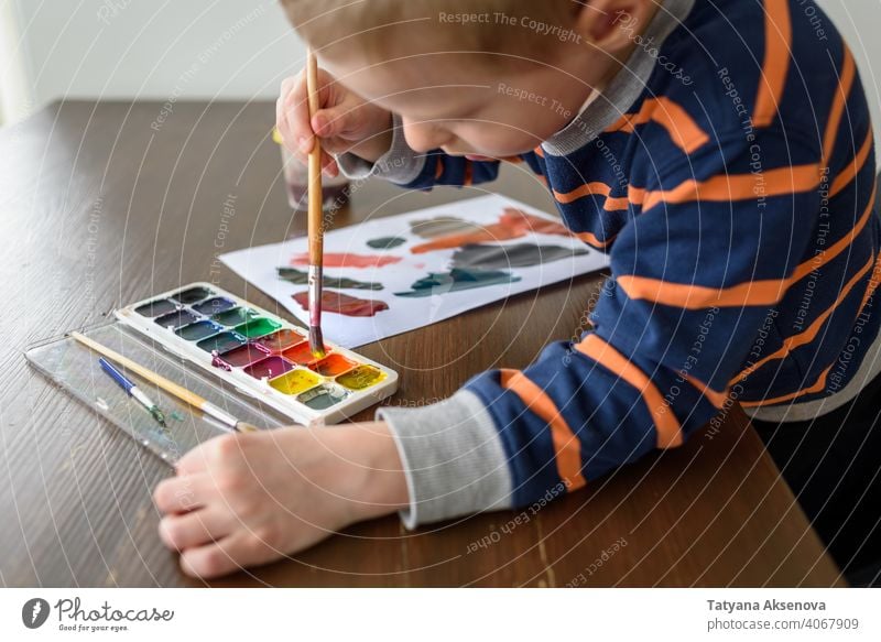 Little boy painting with watercolor child drawing artist hobby paintbrush painter creativity person hand paper young white artwork leisure imagination picture