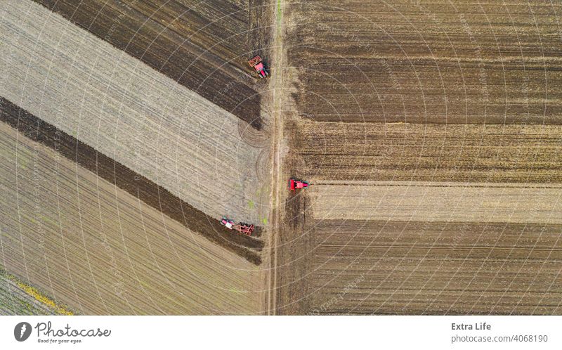 Above top view shot of three tractors, they are pulling machines, over arable field, preparing soil for new crop Aerial Agricultural Agriculture Agriculturist