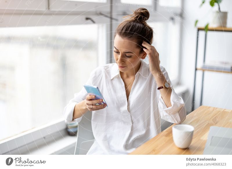 Shot of a young businesswoman using smartphone in an office millennials student hipster indoors loft window natural girl adult attractive successful people