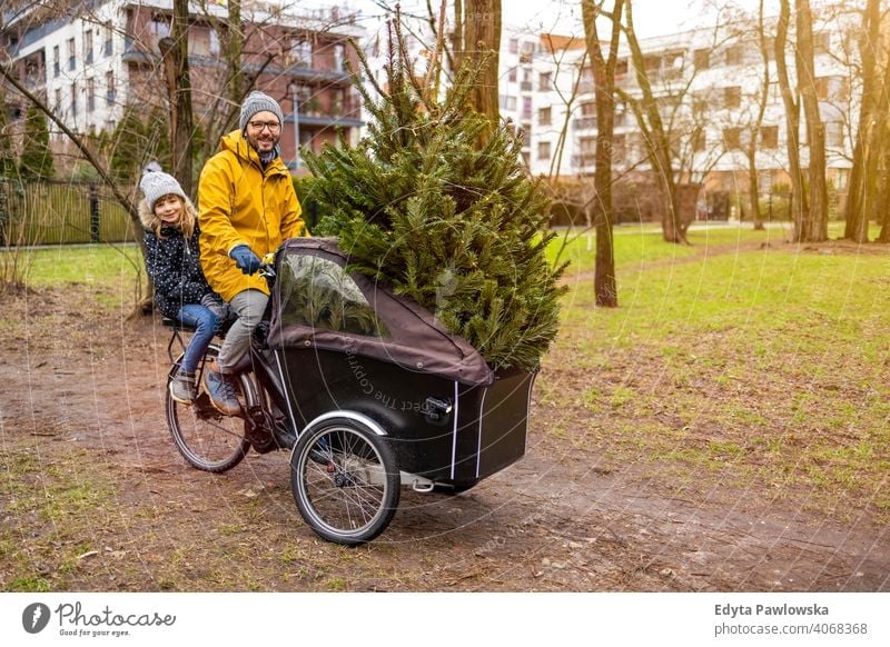 Father and daughter have a ride with cargo bike transporting Christmas tree sustainable transport Tree fun Joy enjoying Hipster Modern Carrying millennial