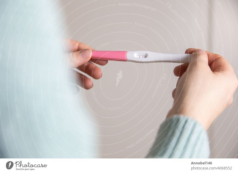 Happy young woman holding a positive pregnancy test close-up bright colors modern stylish design pregnant result female fertility motherhood maternity adult