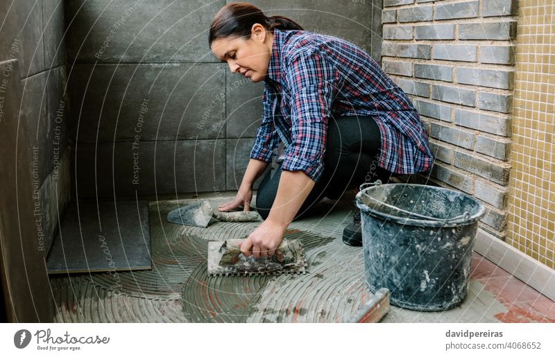 Female mason laying tiles on a terrace woman workman tiling floor imitation cement tile spread tiler glazed terrace working construction tool installing