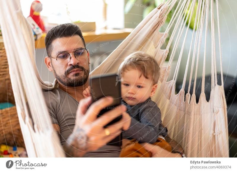 Stay at home dad on smartphone ignoring child single parent single dad fathers day fatherhood stay at home dad paternity leave modern manhood family son house