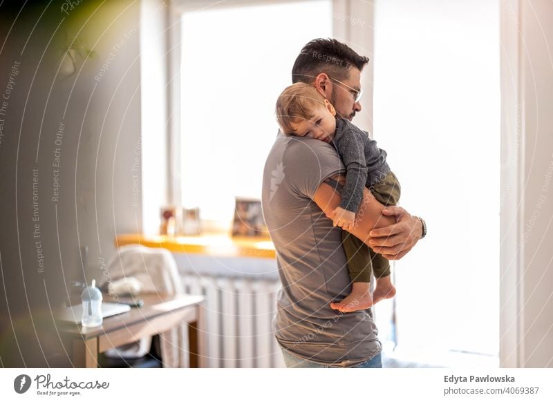Dad putting to sleep baby boy in his arms at home single parent single dad fathers day fatherhood stay at home dad paternity leave modern manhood family son