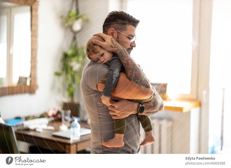 Dad putting to sleep baby boy in his arms at home single parent single dad fathers day fatherhood stay at home dad paternity leave modern manhood family son