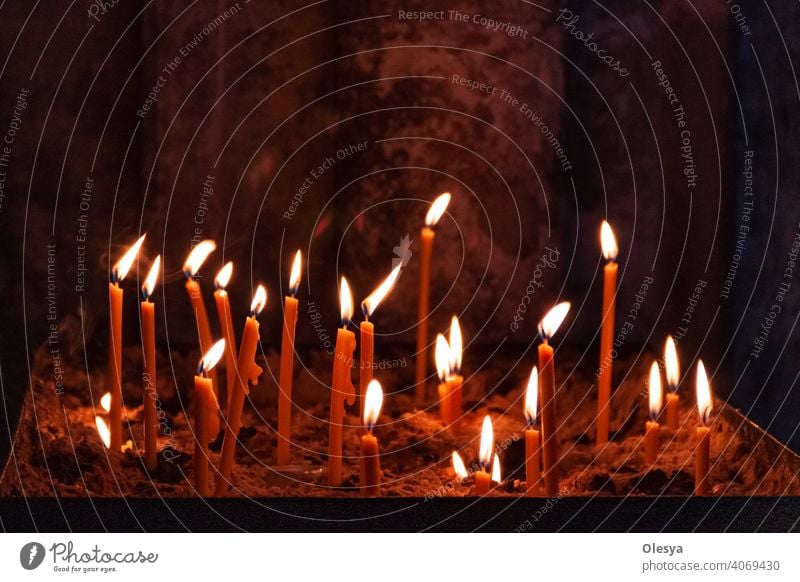 many church candles with varying degrees of burn stuck in the sand in the dark. selective focus. dripping wax from one candle. Belief Spirituality Prayer