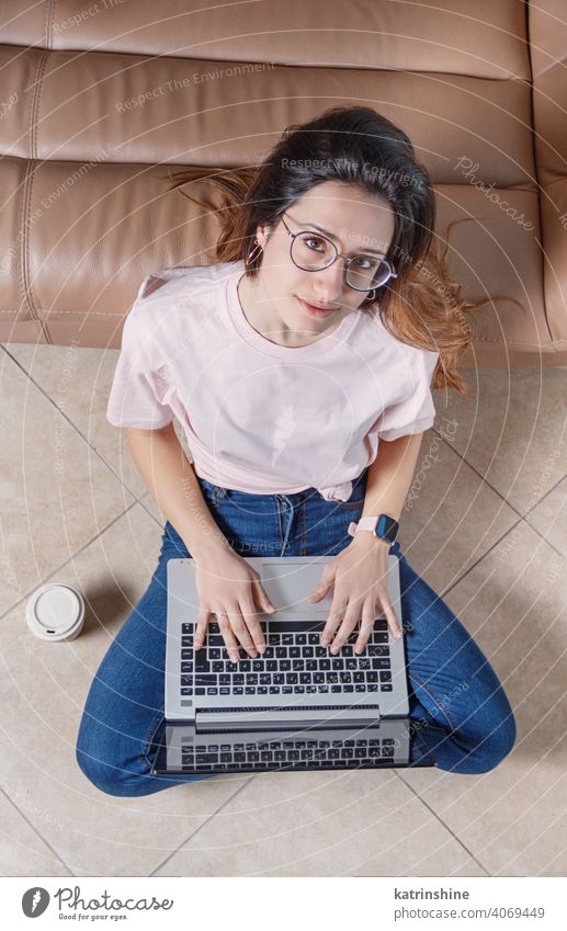 Young women using laptop while sitting on the floor at home wear mockup t-shirt learn student Lifestyle jeans glasses concentrated indoor sofa couch round neck