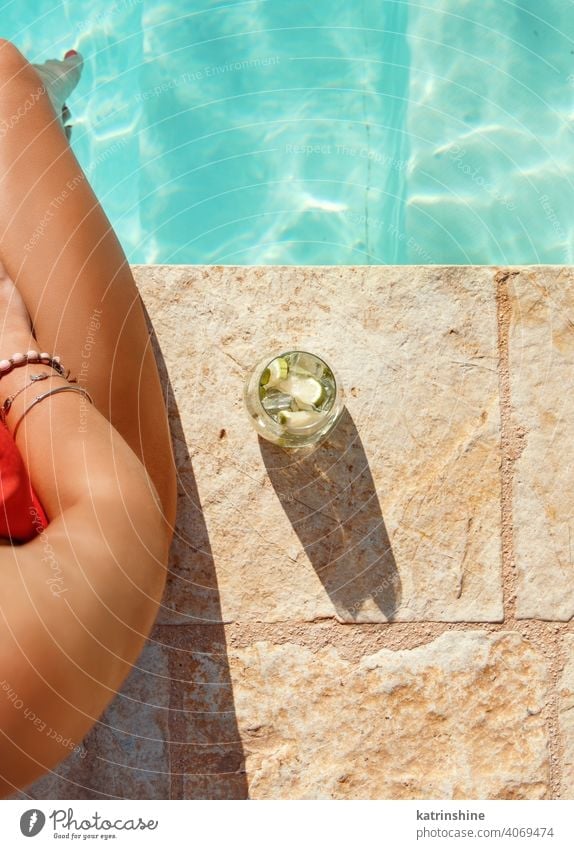 Young woman in red swimsuit with tropical cocktail top view mojito pool faceless legs water one-piece Summer caucasian Fashion alone Happy smile Garden Emotion