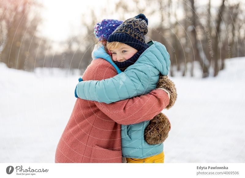 Mother and son hugging outdoors in snow mother daughter season together frozen cheerful fun kid people park holiday forest childhood woman girl nature joy cold