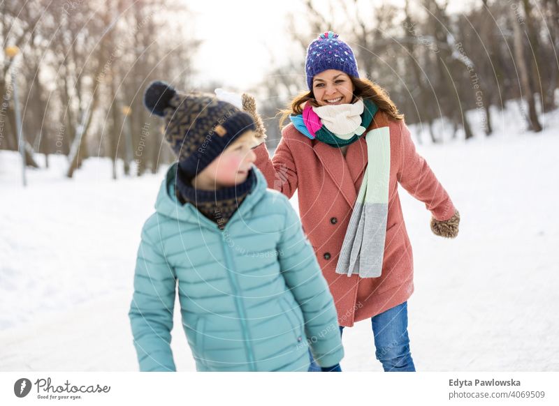 Mother and kid having snowball fight in winter park mother son daughter season together frozen cheerful fun people holiday forest childhood woman girl nature