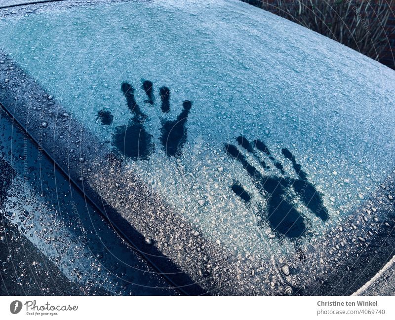 Two handprints on a frozen car rear window, partly shone by the sun Hand Slice Glass silhouettes Car window FRontwheel Ice iced defrosted freezing cold Cold