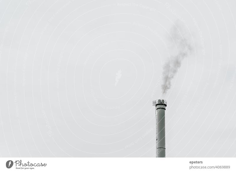 Grey smoke coming out of an industrial chimney in front of a grey sky acid rain air pollution backgrounds business capitalism carbon dioxide carbon footprint