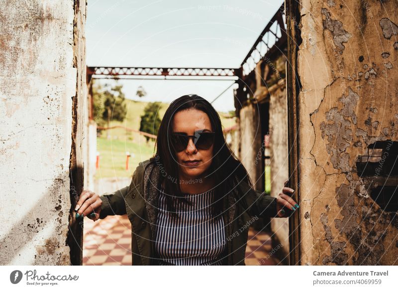 Casual dressed woman in the center of a ruined door frame, closer view outfit outdoors travel vacation ruins casual old structure mosaic sunglasses jacket sunny
