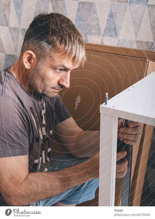 Man assembling furniture with a screewdriver. Housework. Front view. Vertical shot. Close-up man holding screwdriver housework lifestyle father dad repair craft