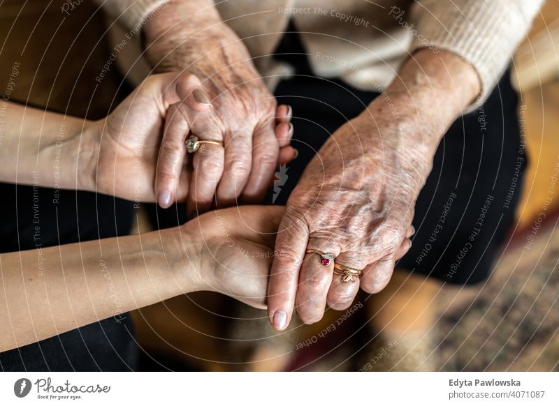 Cropped shot of a senior woman holding hands with a nurse consoling wrinkled real people candid genuine mature female Caucasian elderly aging grandmother