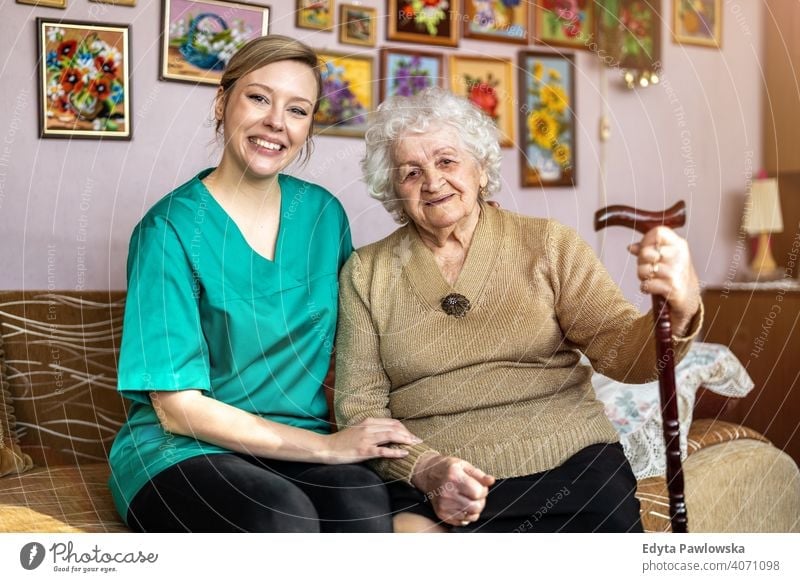 Friendly nurse supporting an elderly lady real people candid genuine woman senior mature female Caucasian home house old aging domestic life grandmother