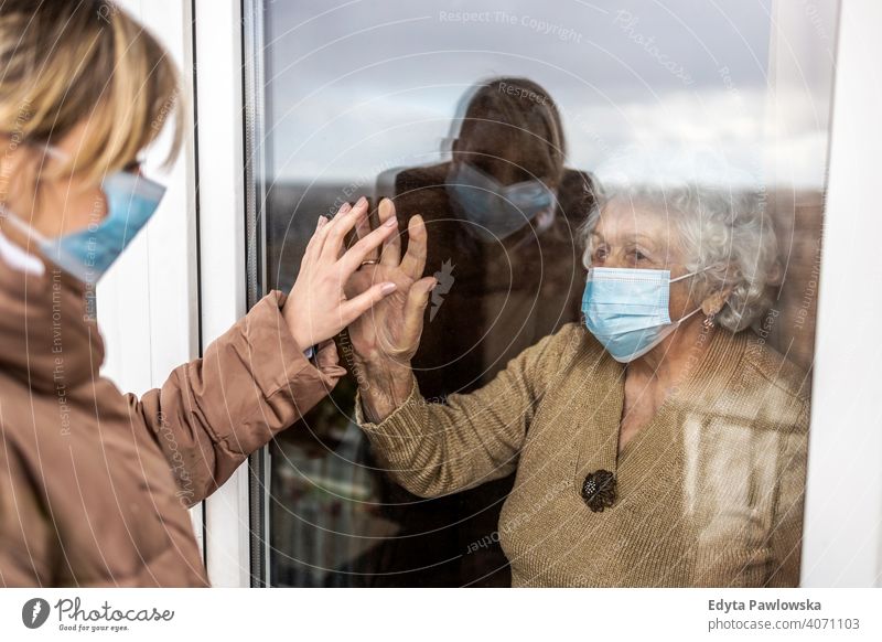 Woman visiting her grandmother in isolation during a coronavirus pandemic window covid lockdown looking quarantine looking through window social distancing