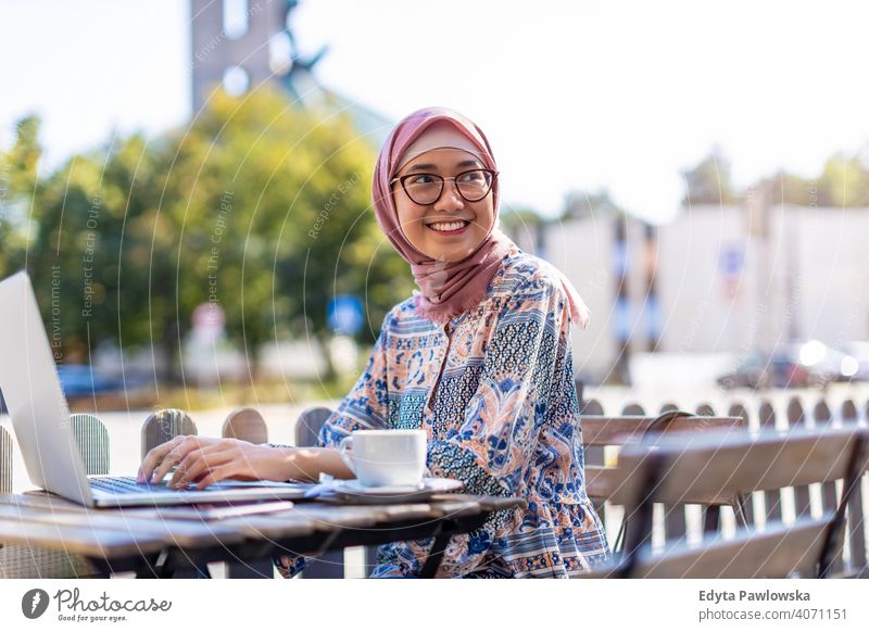 Young Muslim woman using a laptop in outdoor cafe hijab headscarf muslim islam arabic summer girl people young adult female lifestyle active outdoors millennial
