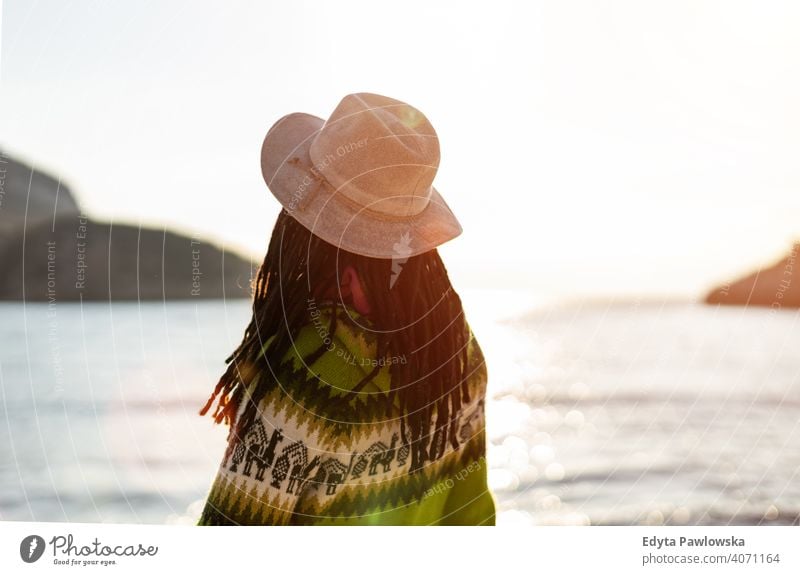 Young woman in a hat on the beach at sunset travel tourist tourism vacation backpacker beautiful attractive young adult people outdoors casual Greece happy joy