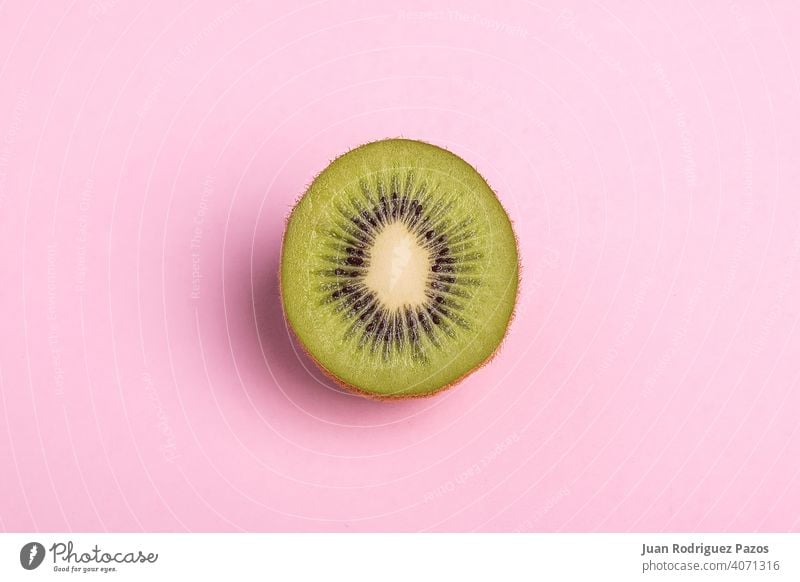 Close-up of a kiwi sliced on pastel pink background. fruit minimal isolated nobody concept healthy cut vegetarian sweet food summer juice color flat green