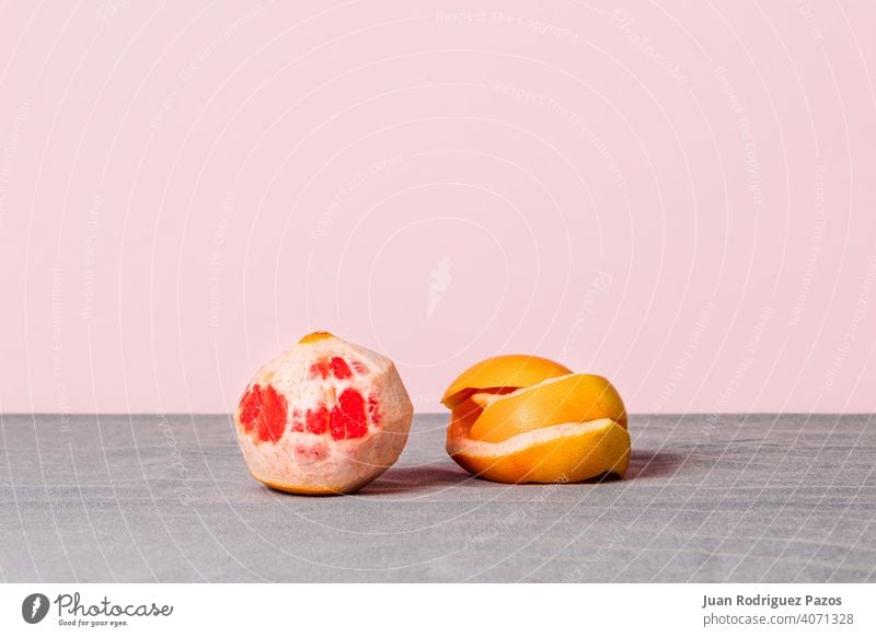 Still life of a peeled grapefruit with its peel beside on a pink background natural seasonal minimalist still life food fresh healthy fit diet detox juicy juice