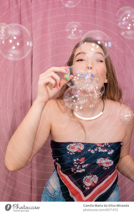 Happy woman making soap bubbles with pink background. adorable beautiful birthday celebration cheerful emotion emotions face fashion female funny girl glamour