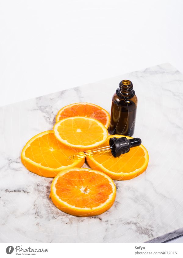 Vitamin C serum bottle with dropper on white marble background vitamin C orange essential oil beauty aromatherapy glass skin care slice bright dark table fruit