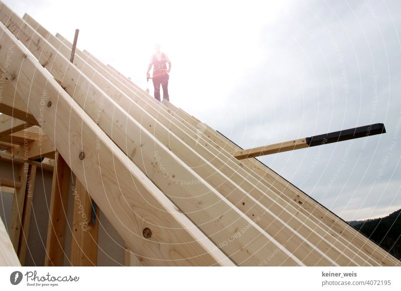 A carpenter standing on a roof truss backlit by the sun like the last craftsman of the nation Build building trade Craft (trade) Craftsperson Construction costs
