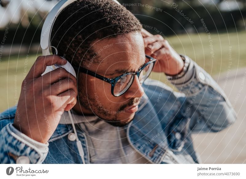 black boy in park listening to music with headphones afro holding youth trendy teenage casual attire skate young portrait sunset lifestyle street skater 1 male