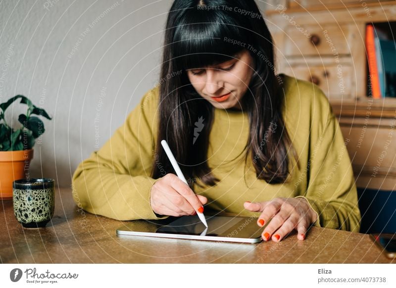 A woman sits at the table and draws or writes something on a tablet Painting (action, artwork) Write Draw pen Ipad Apple Pen Creativity Digital Graphic Designer